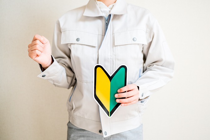 初心者マークを持ちガッツポーズをする作業員